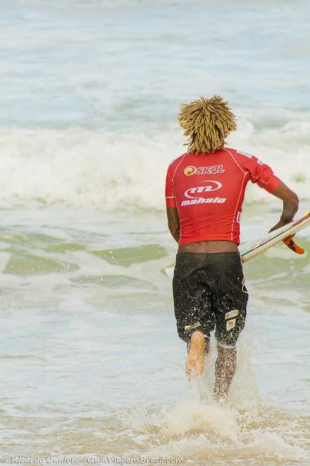 Imagem de surfista correndo para mar da Praia da Tiririca.